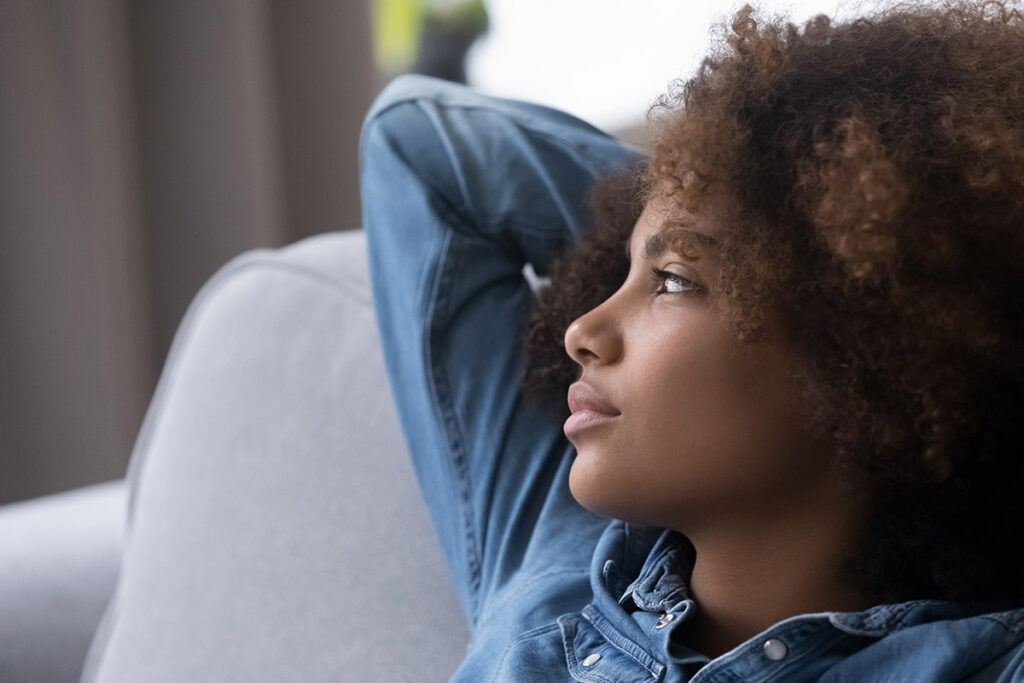 adolescent woman leaning back in a comfortable chair as she contemplates self-care activities to help with anxiety