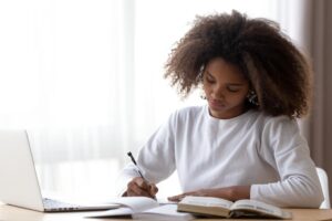 adolescent female student working on her studies as she demonstrates balancing academics and mental health