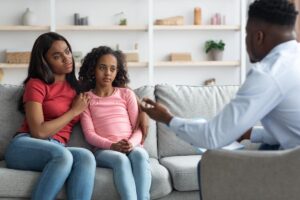 woman with her young daughter asking therapist how does peer pressure affect mental health in children and teens