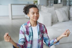 adolescent female integrating mindfulness practics in adolescent treatment for mental health as she assumes a relaxing meditative pose.