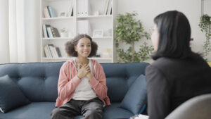 teenage girl smiling excitedly as she discusses 5 benefits of IOP for teens with her mental health specialist.